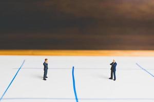 Miniature businessmen standing on an arrow pathway, business decision concept photo