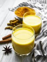 Golden milk with cinnamon, turmeric, ginger and honey over white marble background photo