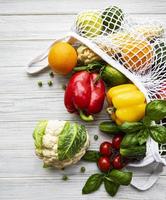 Verduras y frutas frescas en una bolsa de hilo ecológico sobre un fondo de madera blanca foto