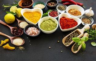 Various spices in a bowls on a black concrete background