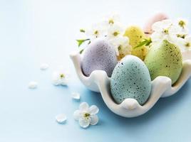 huevos de pascua en bandeja de huevos y flor de primavera foto
