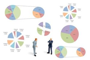 Miniature businessmen standing with charts on a white background photo