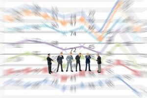 Miniature businessmen standing with charts on a white background photo