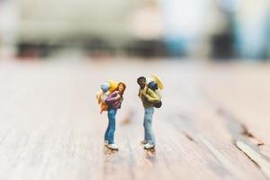 Miniature backpacker tourist people standing on a wooden blurred background photo