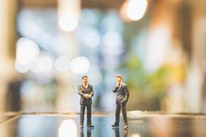 Miniature businessmen standing on glass with a blurred background photo