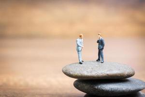 Empresarios en miniatura de pie sobre una piedra, concepto de desafíos y riesgos foto