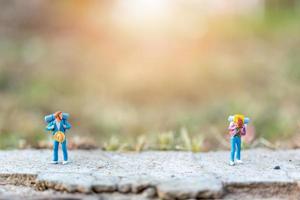 Miniature travelers with backpacks standing on a road, travel and adventure concept photo