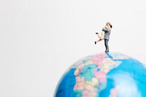 Miniature people standing on a globe with a white background, travel concept photo