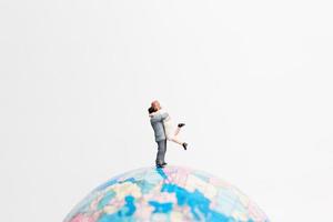 Miniature people standing on a globe with a white background, travel concept photo