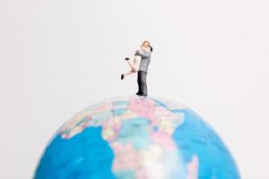 Miniature people standing on a globe with a white background, travel concept photo