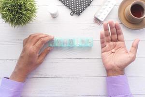 Top view of man's hands taking medicine from a pill box photo