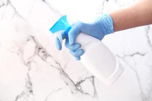 La mano de la persona en guantes desechables con spray desinfectante