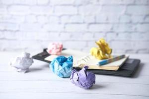 Crumpled paper balls and notepad on wooden table photo