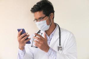 Young doctor talking to smart phone camera in video chat photo