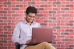 Young man using laptop while sitting in a chair photo