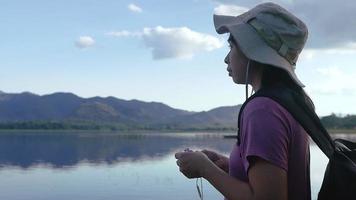 Young Female Tourist Listening to Music on Beautiful Sunset Lake Background video