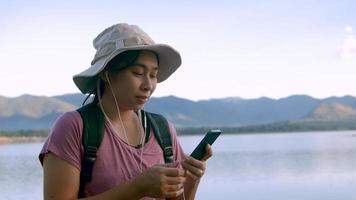jovem turista feminina tirando uma selfie com montanhas e um lago video
