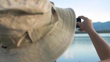 Jeunes femmes touristes à prendre des photos de montagnes et d'un lac au coucher du soleil video