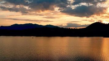 reflektionen av den gyllene himlen på vattenytan och bergen i bakgrunden video