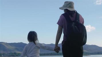 mãe asiática e filha apreciando a vista das montanhas e do lago ao pôr do sol video