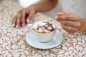 revolviendo un capuchino con una cuchara foto