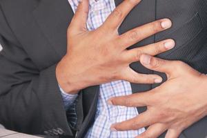 Young man suffering pain in heart and holding chest with hand photo