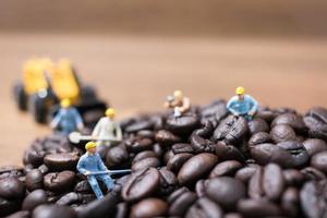 Gente en miniatura trabajando en granos de café tostados.