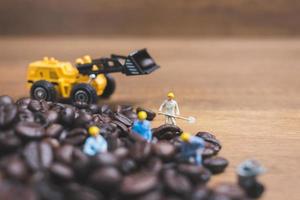 Gente en miniatura trabajando en granos de café tostados. foto