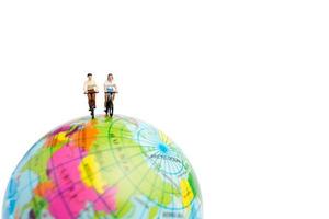 Miniature travelers with bicycles on a globe on a white background photo