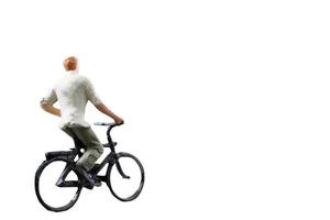 Miniature figure riding a bicycle isolated on a white background photo