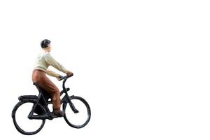 Miniature figure riding a bicycle isolated on a white background photo
