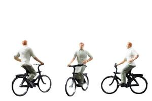 Miniature figure riding a bicycle isolated on a white background photo