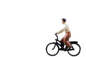 Miniature figure riding a bicycle isolated on a white background photo