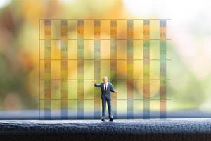 Miniature businessman standing in front of a graph chart background photo