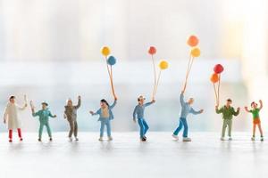 Gente en miniatura caminando con globos, concepto de familia feliz