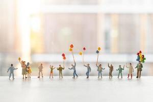 Miniature people walking with balloons, happy family concept photo