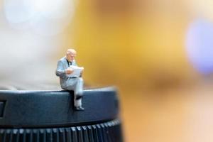 Miniature businessman sitting with a colorful bokeh background photo