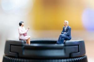 Miniature businesspeople sitting with a colorful bokeh background photo