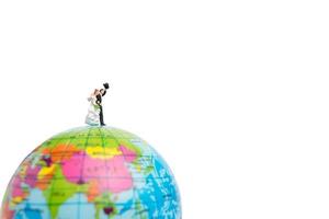 Miniature wedding, bride and groom couple on a globe on a white background photo