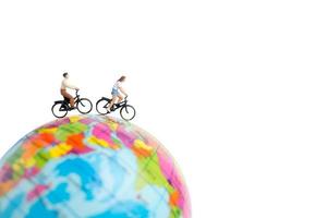 Miniature travelers with bicycles on a globe on a white background photo