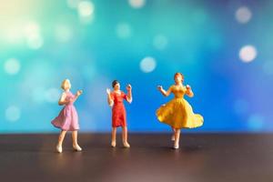 Mujeres en miniatura en vestidos de colores bailando sobre un fondo bokeh foto