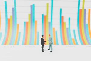 Miniature businessmen standing on a chart background photo