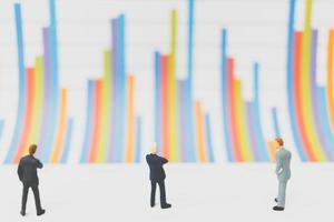 Miniature businessmen standing on a chart background photo
