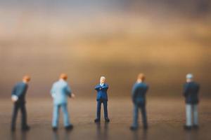 Miniature businesspeople standing on a wooden background photo