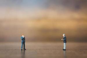 Miniature businesspeople standing on a wooden background photo