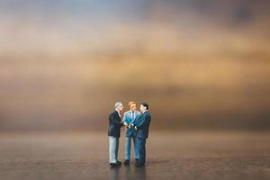 Miniature businesspeople standing on a wooden background photo