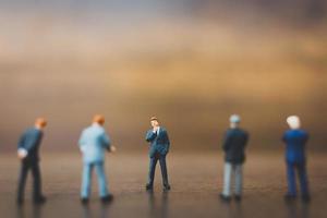 Miniature businesspeople standing on a wooden background photo
