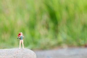 Viajero en miniatura con una mochila de pie y caminando en un prado foto