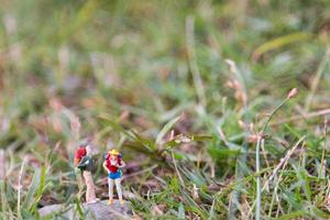 Viajeros en miniatura con mochilas de pie y caminando en un prado foto