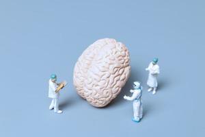 Médicos en miniatura que controlan y analizan un cerebro en busca de signos de la enfermedad de alzheimer y la demencia, el concepto de ciencia y medicina